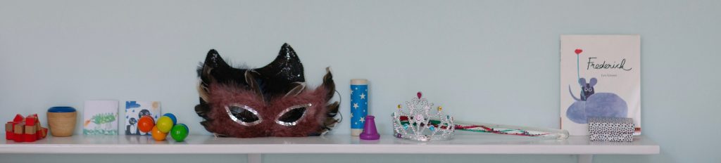 Kaleidoskope, eine Krone, ein Zauberstab, Memorykarten, ein Kinderbuch und Holzspielzeug in der Psychotherapiepraxis